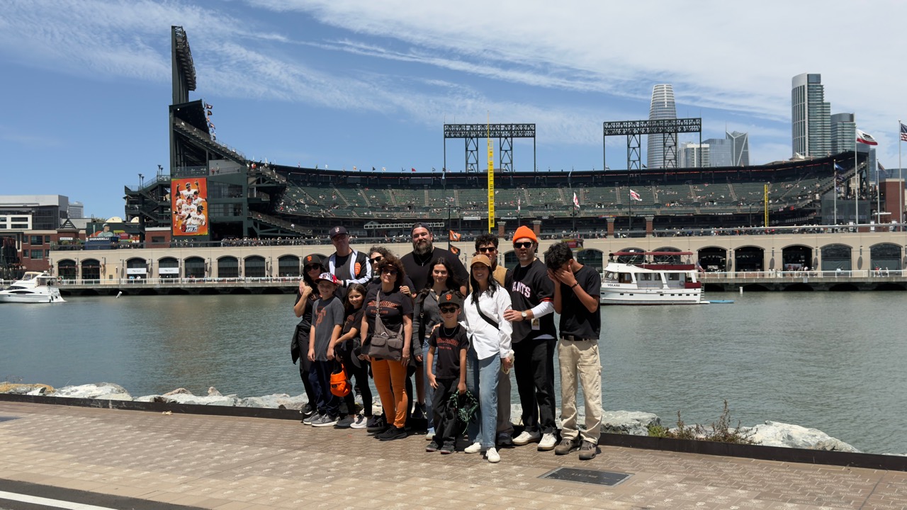Family posing across McCovey Cove with Oracle Park behind them.